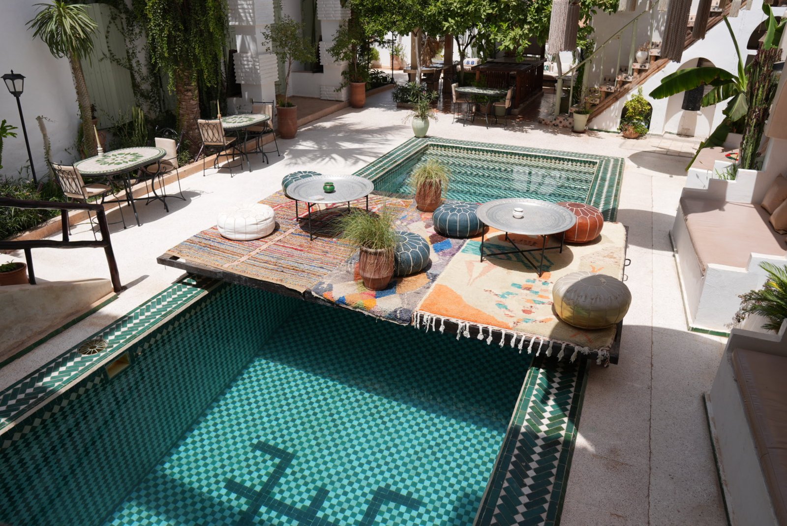 Courtyard pool of Riad Dar Salam Souss with a wooden platform, rugs and poufs