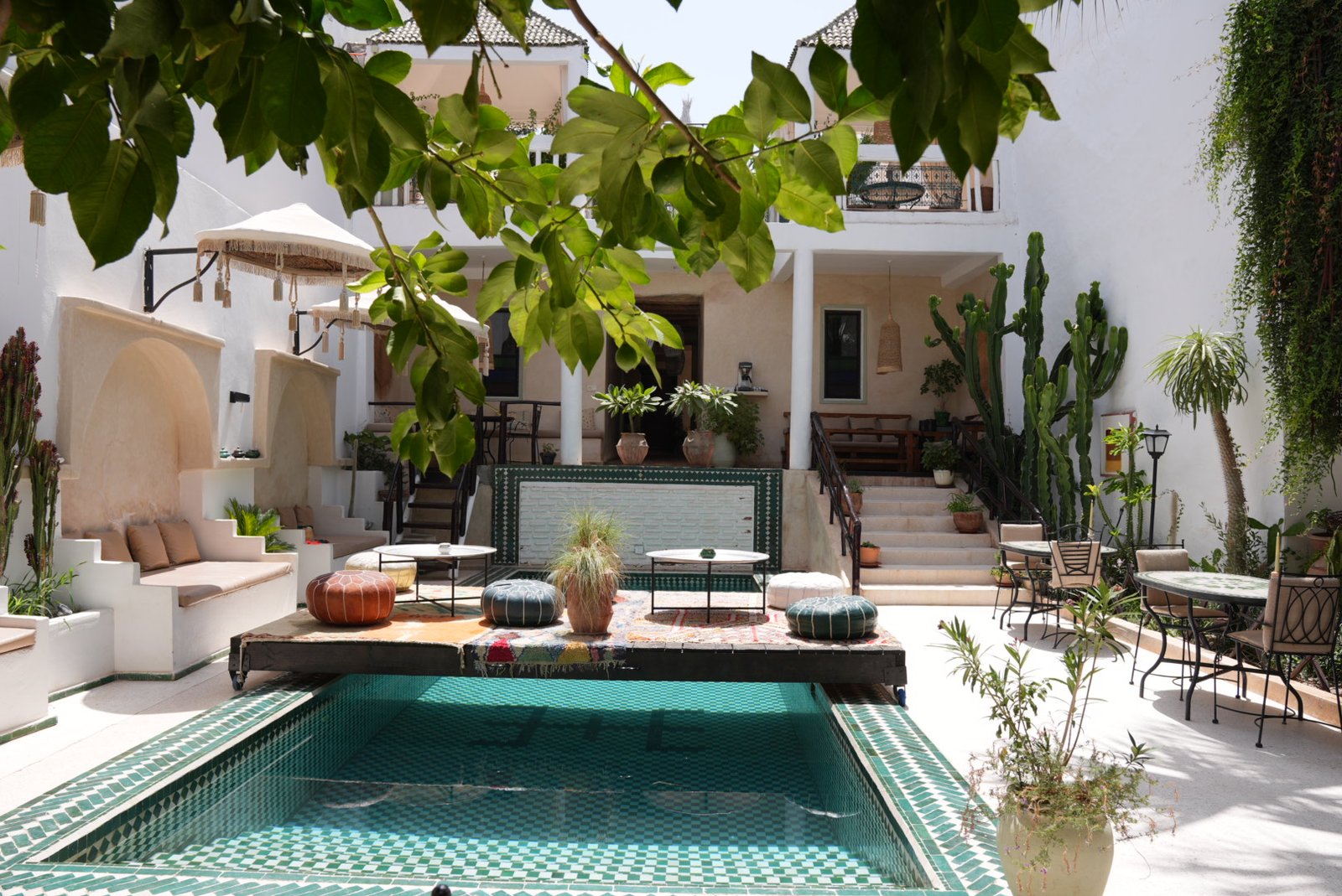 Poolside sofas under umbrellas, palms around the courtyard